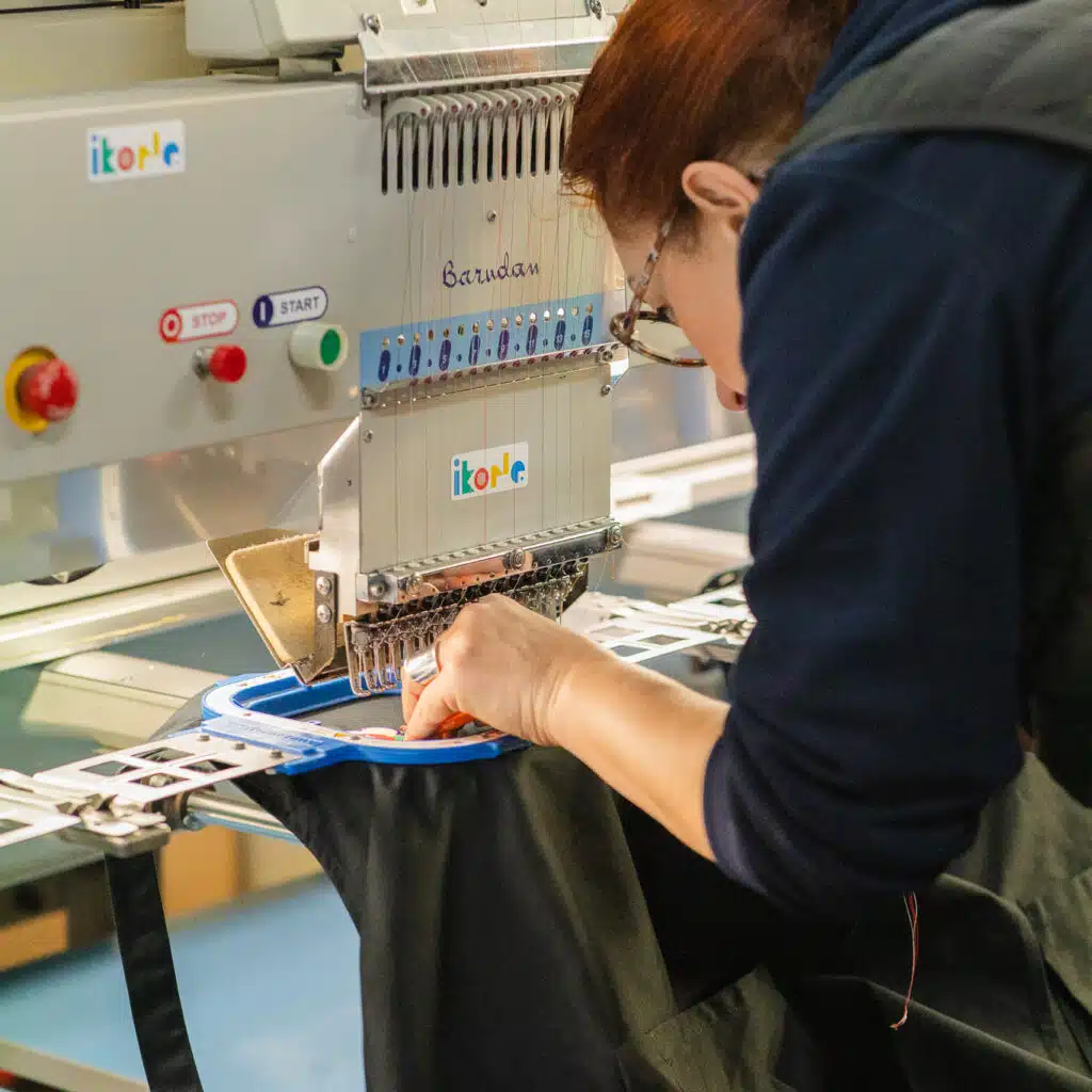 opératrice positionnant un textile dans le tambour d'une machine à broder